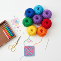 Crochet kit with colorful yarn balls, hook set, scissors and stitch markers on white background