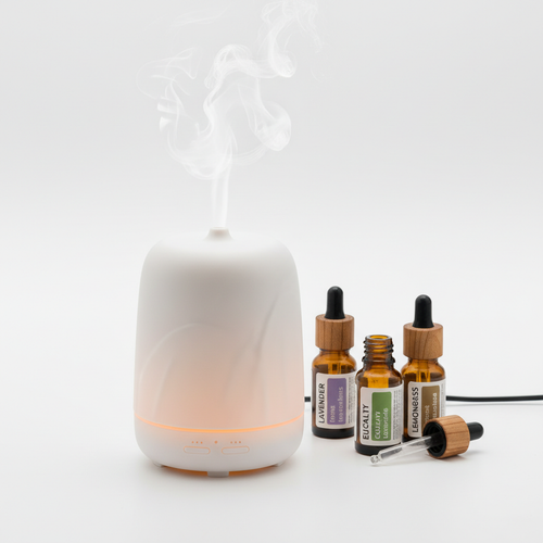 Sleek ultrasonic aromatherapy diffuser with soft mist and essential oil bottles on white background